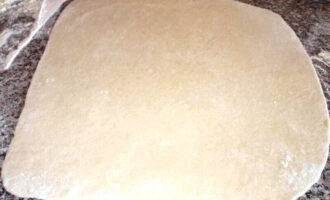 С помощью скалки и муки раскатываем тесто в прямоугольник толщиной 3-4 мм .
