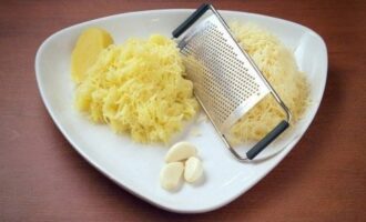 Натираем вареный картофель и сыр на мелкой терке, чеснок пропускаем через пресс.